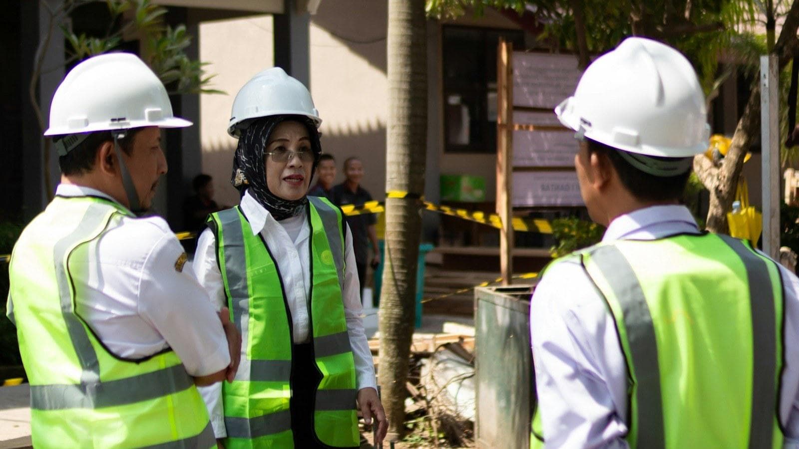 Pekerja dengan helm dan rompi keselamatan berdiskusi saat safety induction sebelum mulai bekerja